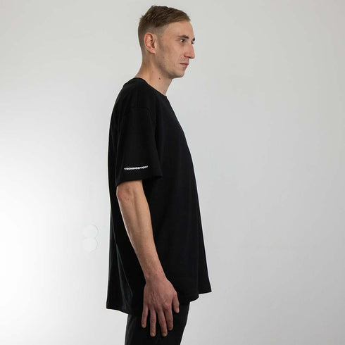 schwarzes oversized "Stoff hoch 4" Raver T-Shirt von der Seite, getragen von einem MAnn